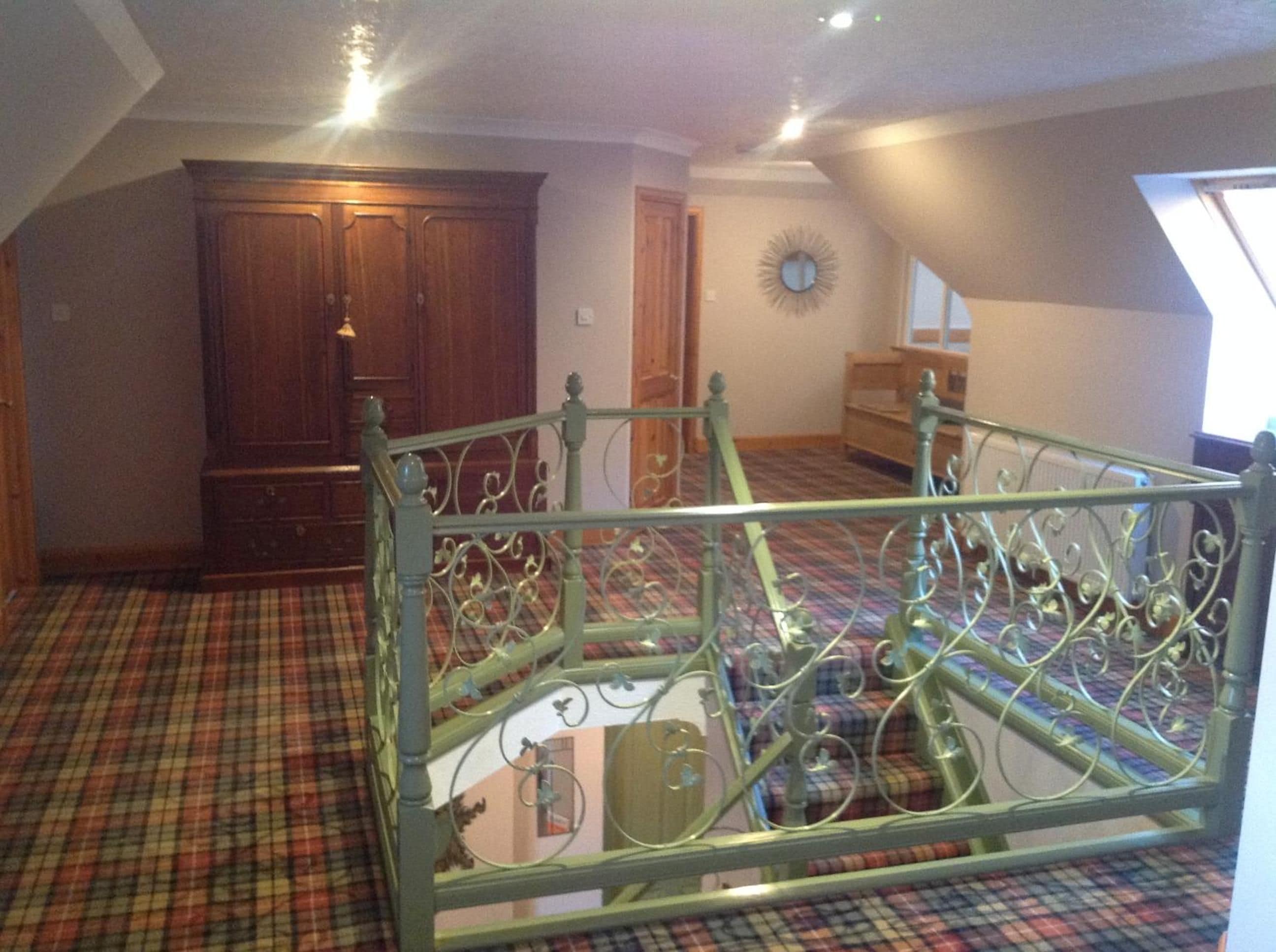 A room with a metal bed frame, a plaid carpet, a wooden wardrobe, and a window.