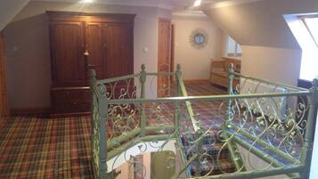 A room with a metal bed frame, a plaid carpet, a wooden wardrobe, and a window.