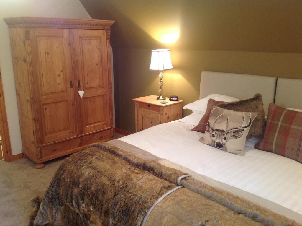 Une chambre à coucher avec une grande armoire en bois, une table de chevet avec une lampe et un lit doté de plusieurs oreillers.