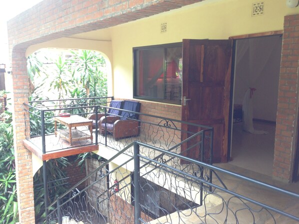 Un balcon avec une table et des chaises, une fenêtre et une porte donnant sur un espace intérieur.