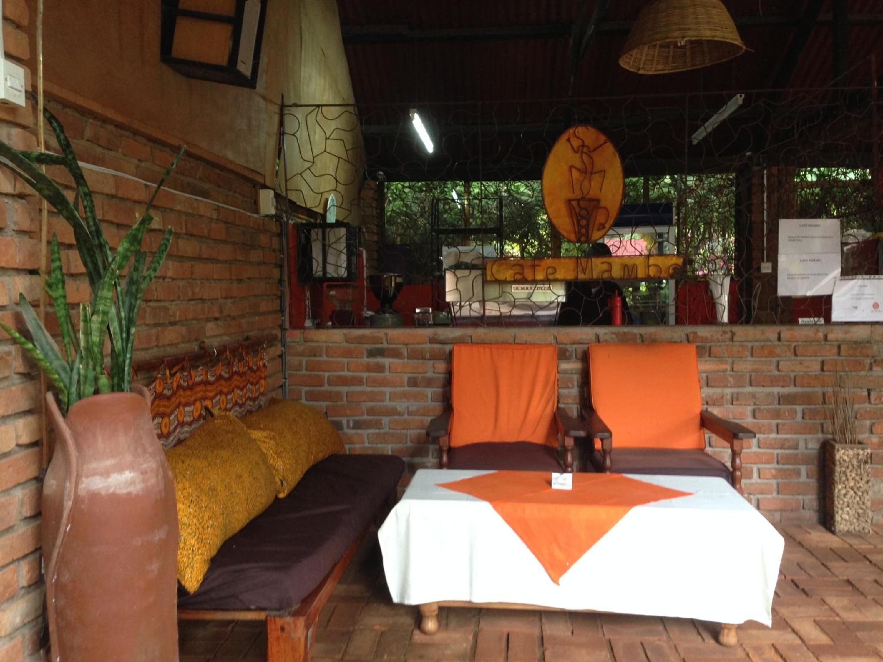 A rustic outdoor seating area with a brick wall, a cushioned bench, and a table with a white tablecloth.