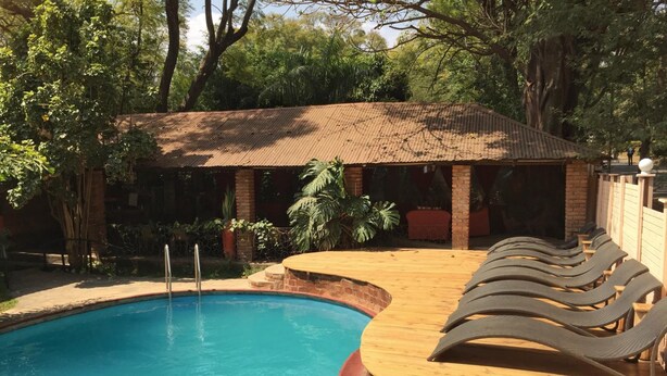 A pool area with a wooden deck and lounge chairs. - Outpost Lodge (Arusha)