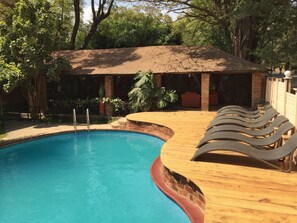 Un espace piscine doté d’une terrasse en bois et de chaises longues.