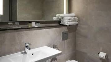 Un baño moderno con un lavamanos blanco, un inodoro y un espejo grande.