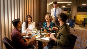 A group of people dining at a table in a modern hotel room with a striped wall and a patterned carpet. - Maldron Hotel South Mall Cork City (Cork)