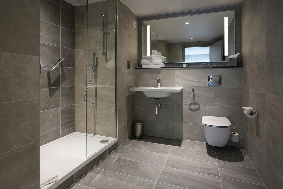 A modern bathroom with a glass-enclosed shower, a sink, and a toilet.