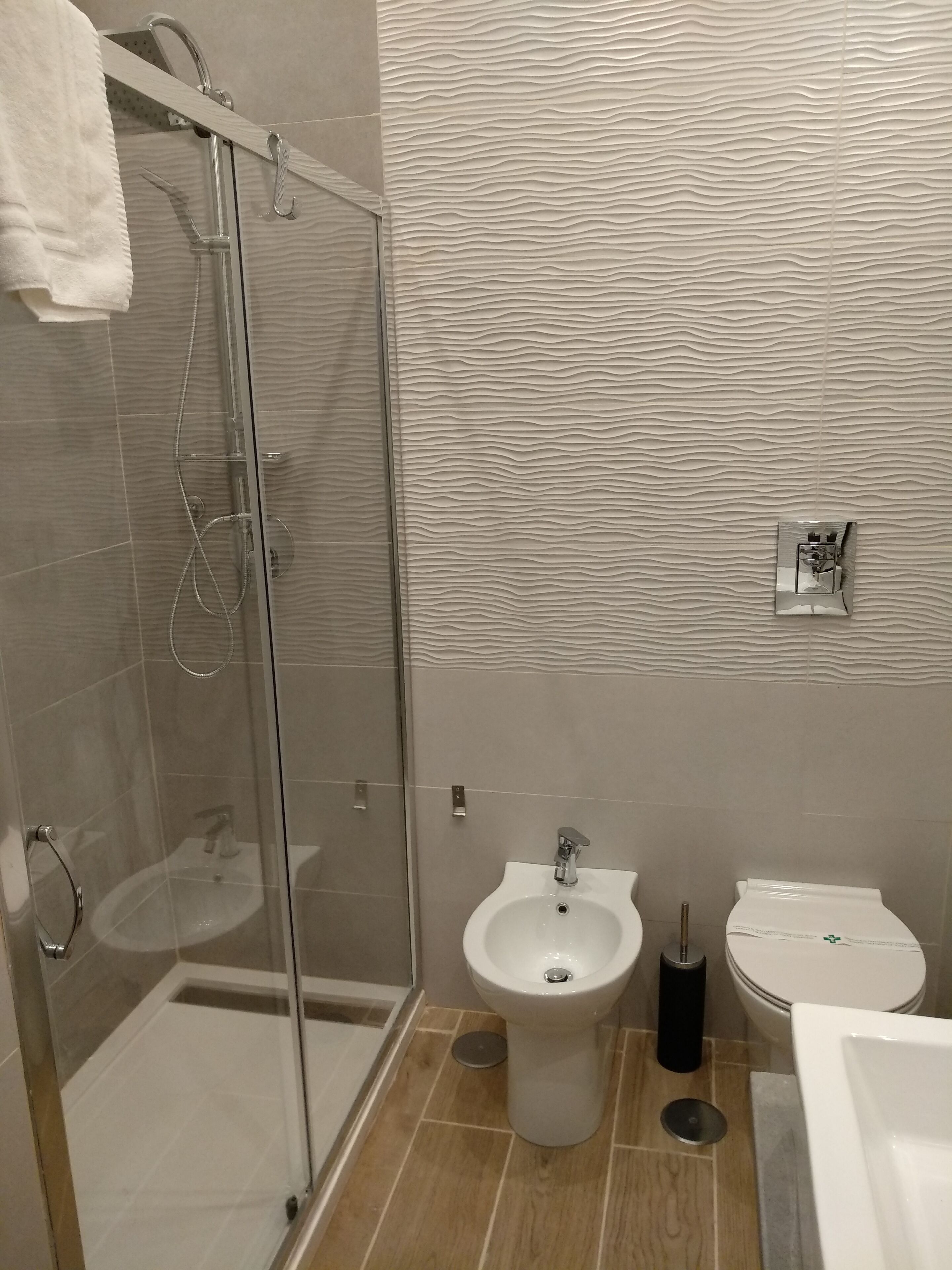 A modern bathroom with a glass shower enclosure, a pedestal sink, and a toilet.