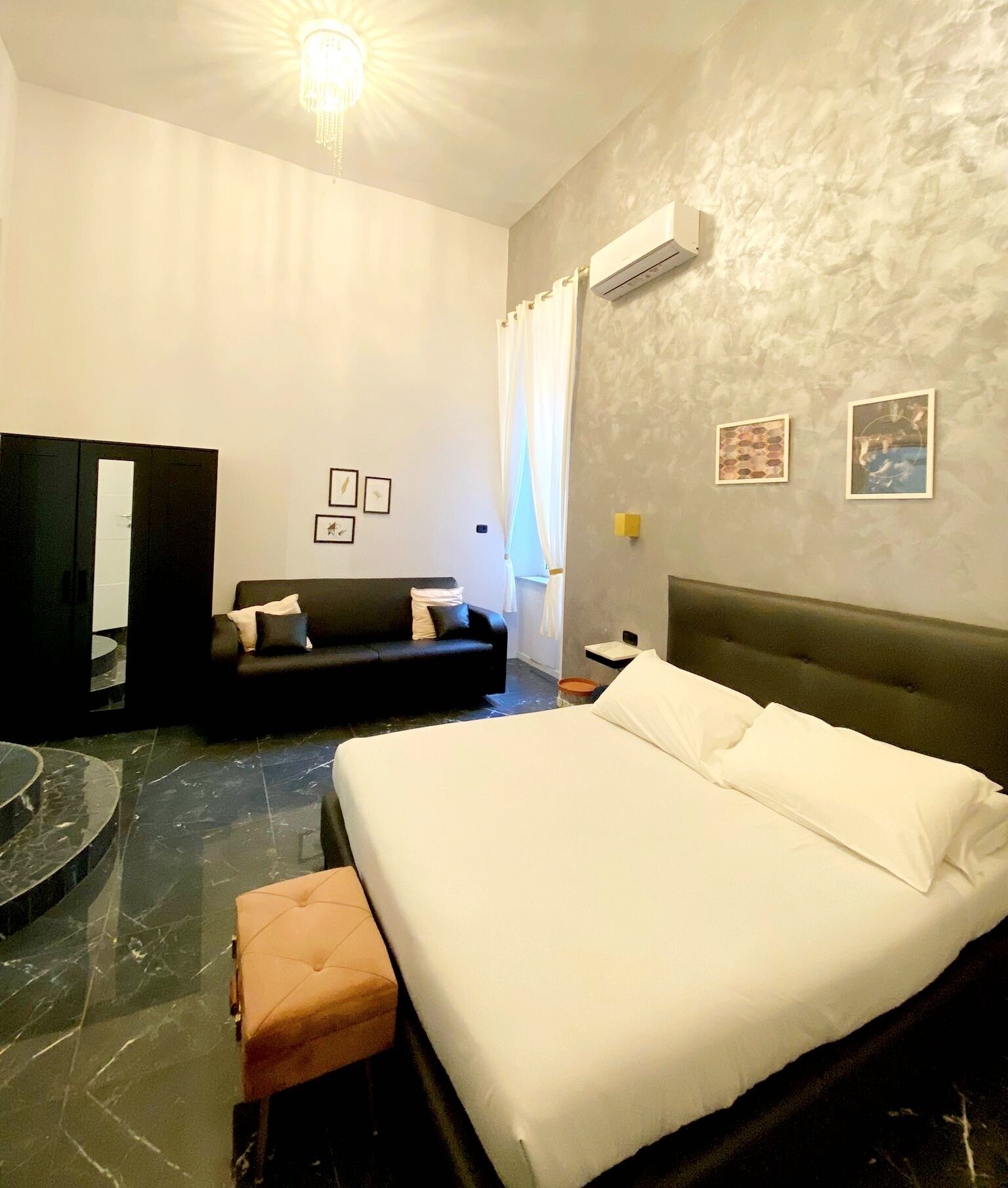 Une chambre avec un grand lit, un canapé, une petite table et un miroir.