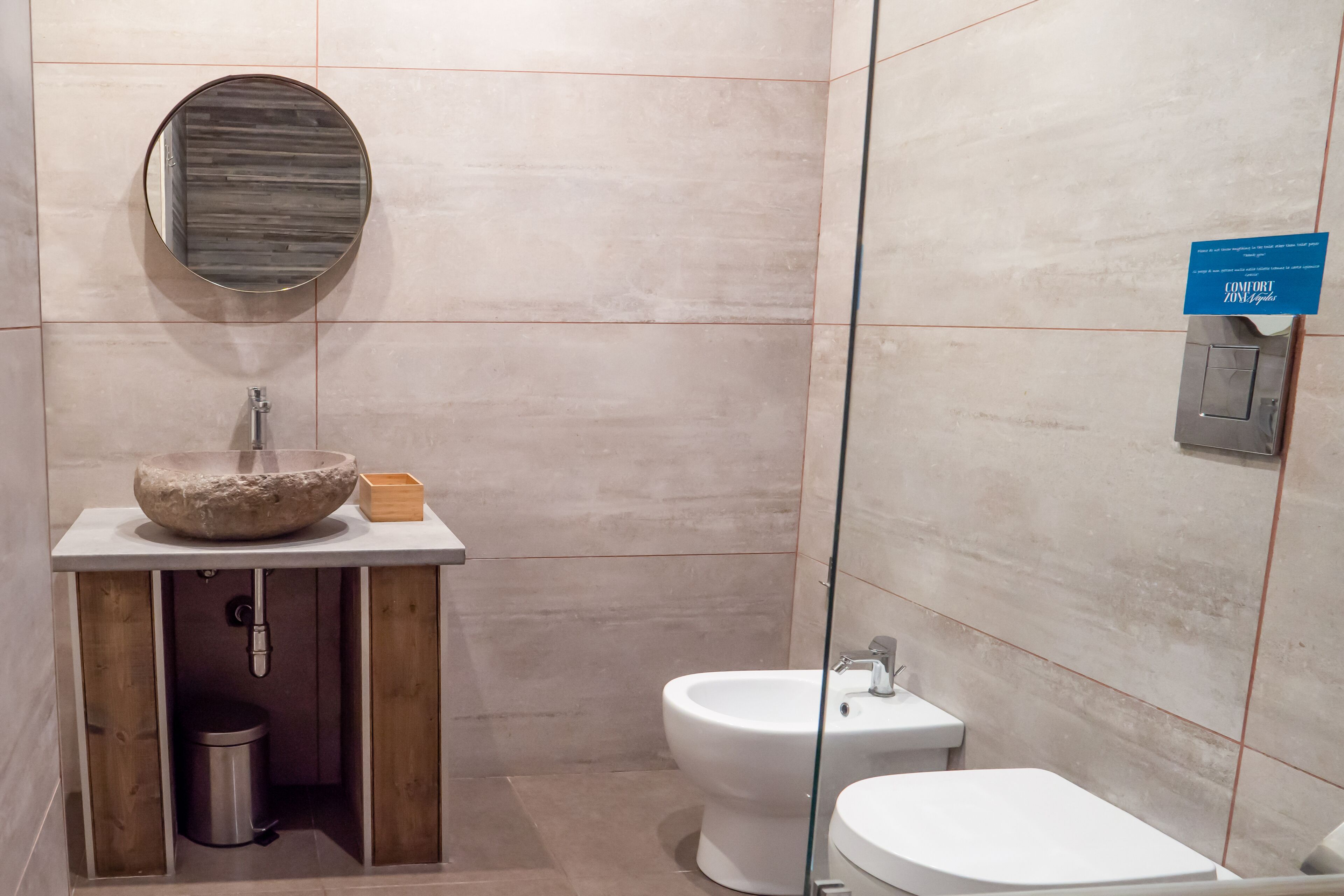 A modern bathroom with a stone sink, a bidet, and a toilet.