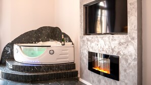 A modern bathroom with a spa tub, a fireplace, and a mounted TV. - Comfort Zone Naples (Naples)