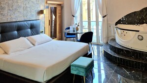 A hotel room with a bed, a small table with chairs, a bathtub, and a large window with curtains. - Comfort Zone Naples (Naples)