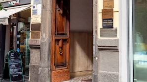 A building facade with a wooden door, a sign for 'Customer Service', and multiple business signs including 'Gran Caffè Pasquari' and 'Toraldo'. - Comfort Zone Naples (Naples)