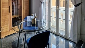 A room with a glass table and chairs, a wooden cabinet, and a view of buildings through large windows. - Comfort Zone Naples (Naples)