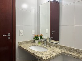 Un baño con lavamanos de encimera de granito, un espejo y una planta en maceta.