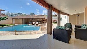 An outdoor swimming pool area with lounge chairs and a covered patio. - SAN GIACOMO I Apartamentos por temporada no Porto das Dunas (Aquiraz)