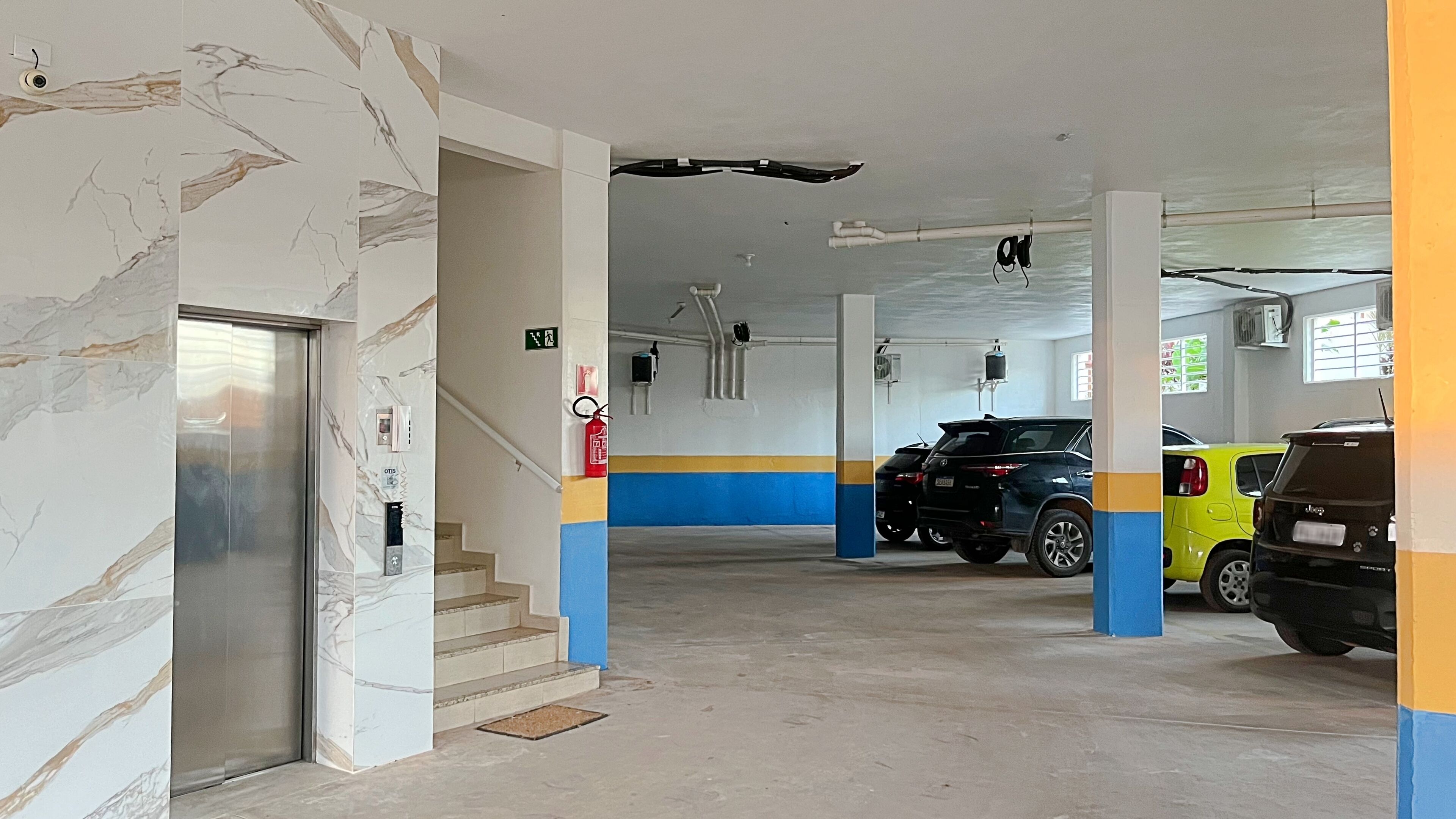 A parking garage with a marble wall, a fire extinguisher, and a staircase.