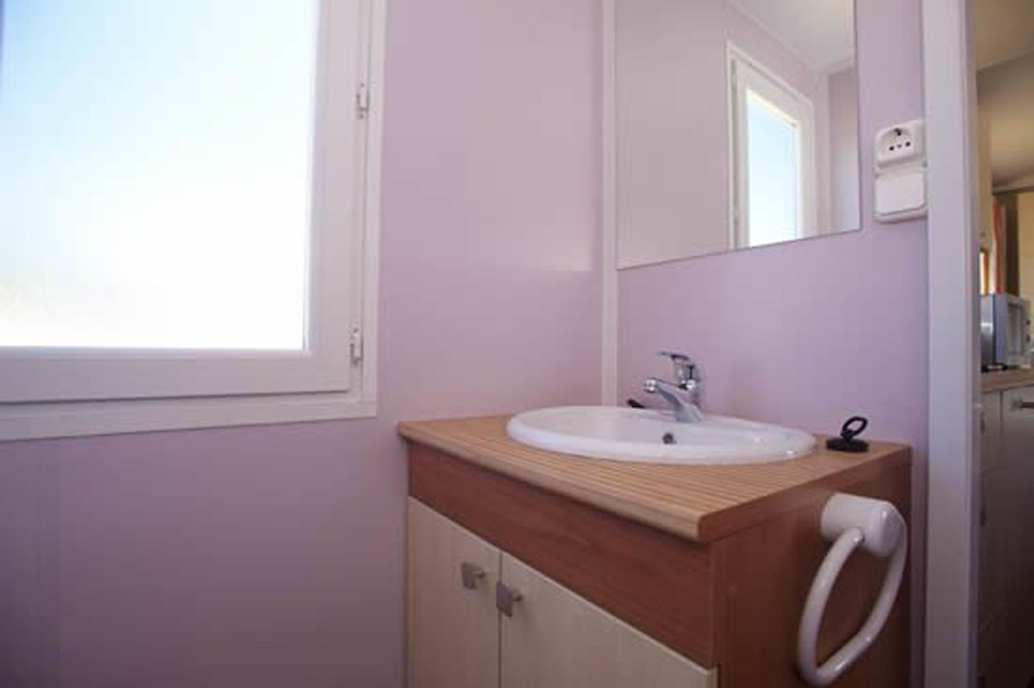 A bathroom with a wooden vanity, a white sink, and a mirror.