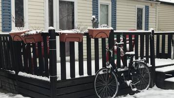 Un espace extérieur enneigé, avec un vélo garé près d’une clôture en bois.