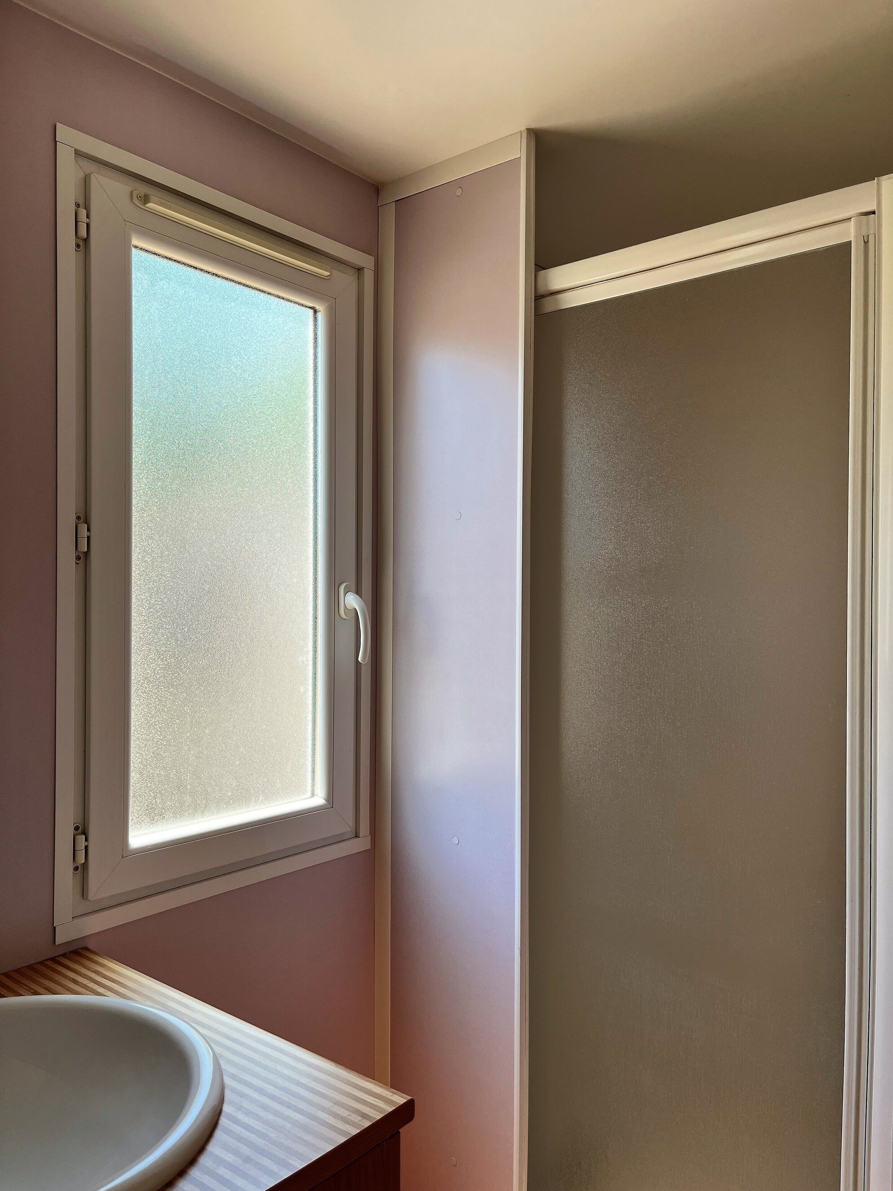 Un baño con ventana, lavamanos y ducha.
