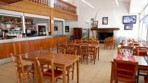 Ein Restaurant mit Holztischen und -stühlen, einer Bar und einem Kamin.