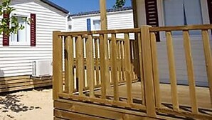 Ein Bungalow mit Holzterrasse und kleiner Veranda.