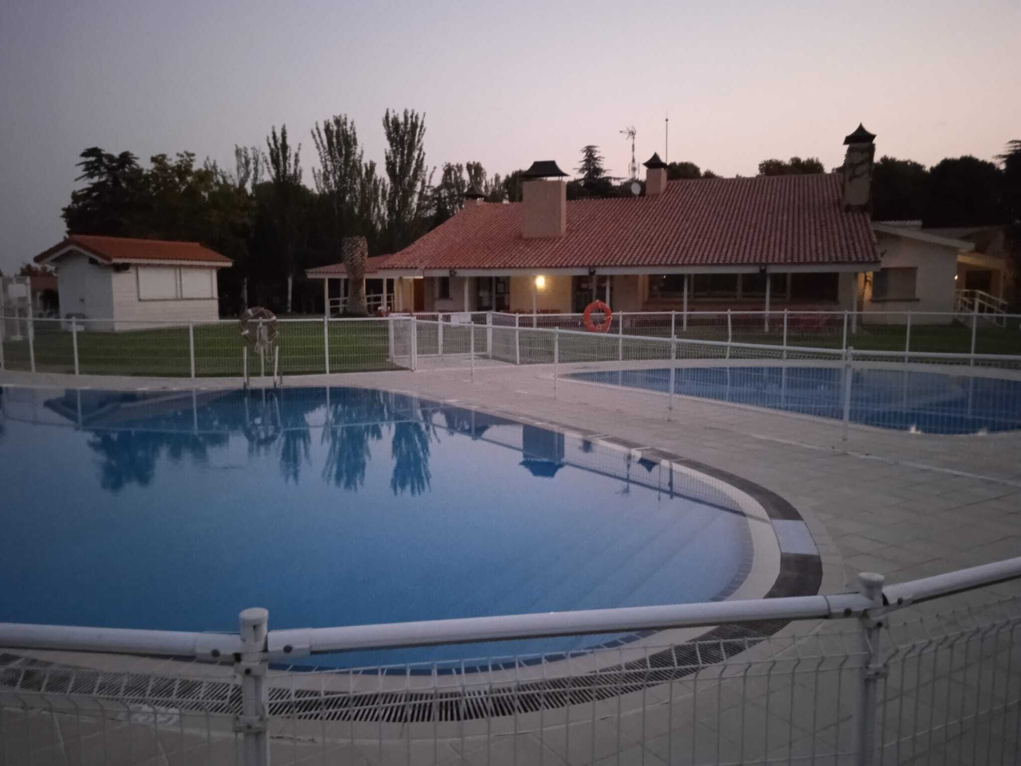 Una piscina con borde de azulejos y una valla.
