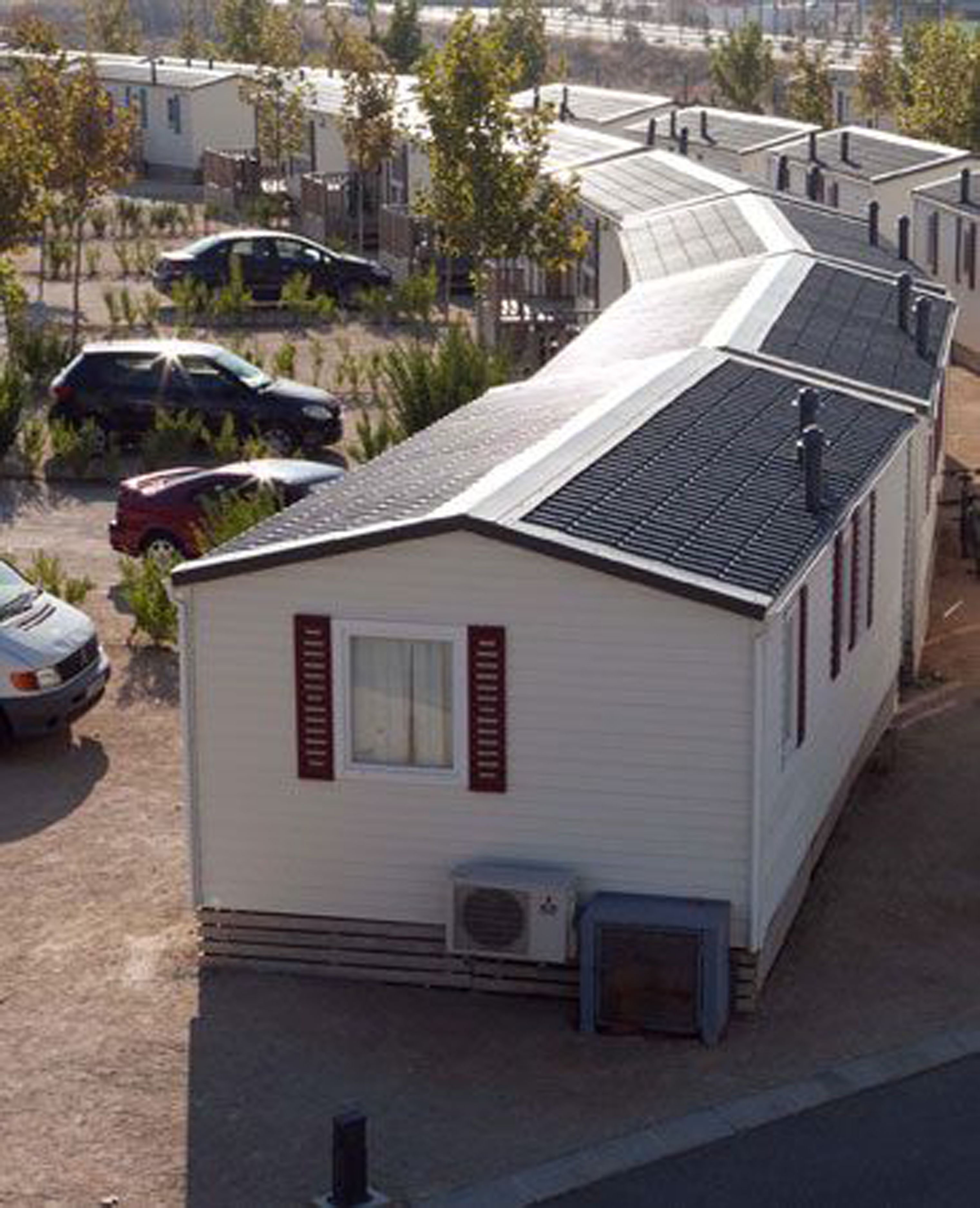 Ein Wohnmobil mit einer kleinen angeschlossenen Garage, einem Fenster mit Rollläden und einer Klimaanlage.