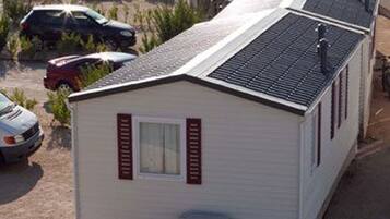 Ein Wohnmobil mit einer kleinen angeschlossenen Garage, einem Fenster mit Rollläden und einer Klimaanlage.