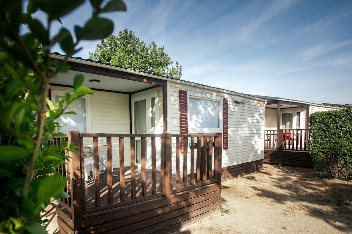 Uma casa móvel com um deck de madeira e varanda coberta.