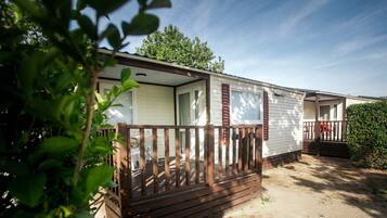 A mobile home with a wooden deck and a covered porch.