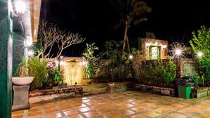 A courtyard with a tiled floor, potted plants, and a brick wall. - Land of joy Ubud Hall (Hengchun)