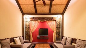 A cozy living room with a wooden coffee table, two sofas, and a TV on a red wall. - Land of joy Ubud Hall (Hengchun)