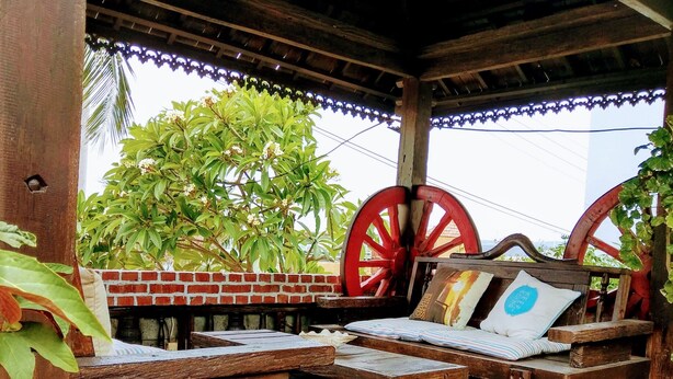 A wooden deck with benches and a table, surrounded by a brick wall and a palm tree. - Land of joy Ubud Hall (Hengchun)