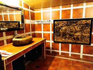 A bathroom with a stone sink, a mirror, and a wall-mounted sculpture. - Land of joy Ubud Hall (Hengchun)