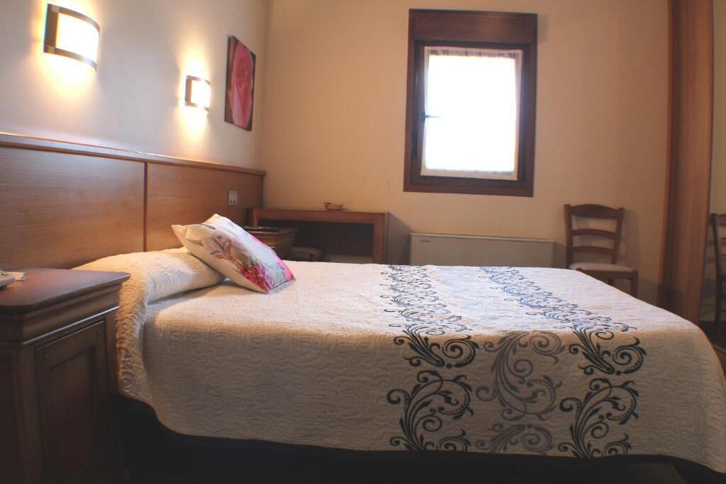 Una cama bien tendida con una colcha estampada, una mesita de noche y una lámpara de noche.