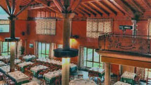 A spacious restaurant with high wooden ceilings and multiple dining tables set for guests. - Hostal Oianume (Urnieta)