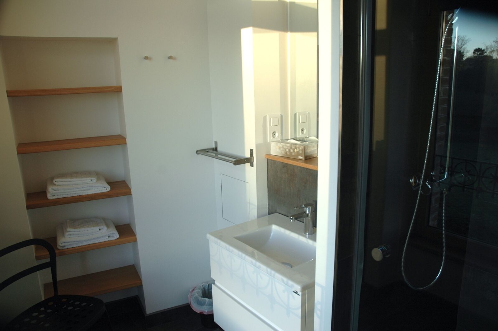 Een badkamer met een wastafel, spiegel, handdoekhouder en douche.