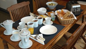 Een ontbijt opstelling met een broodrooster, brood en diverse ontbijtartikelen op een houten tafel.