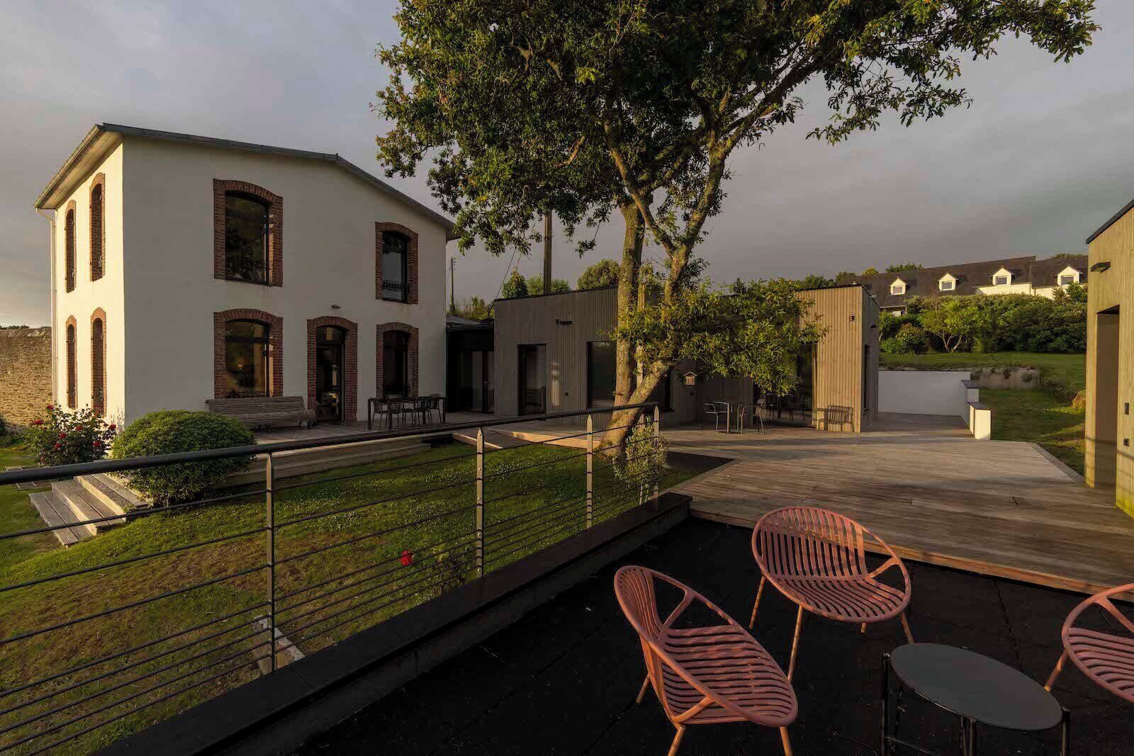 A modern house with a patio area, outdoor seating, and a garden.