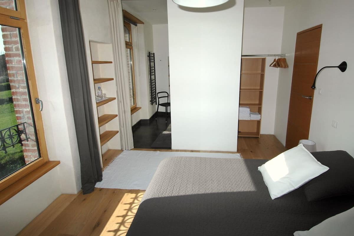A bedroom with a bed, a window, a wardrobe, and a chair.