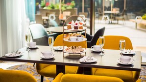 A dining table set with a tiered dessert stand, plates, cups, and cutlery. - Maldron Hotel Newcastle (Newcastle-upon-Tyne)