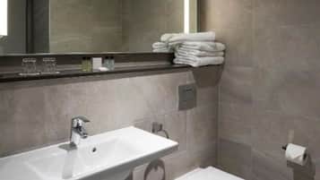 A modern bathroom with a large mirror, a sink, and a toilet.