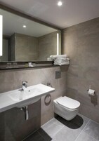 A modern bathroom with a large mirror, a sink, and a toilet.