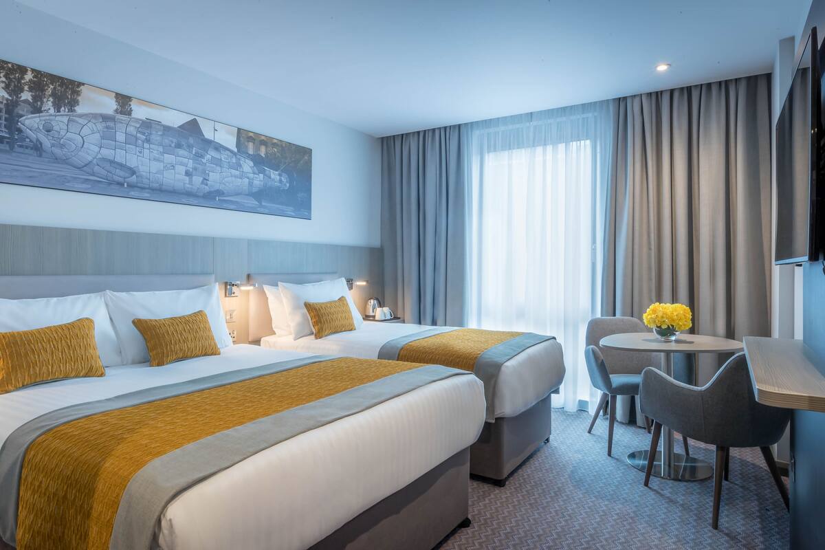 A hotel room with two beds, a desk, and a chair.