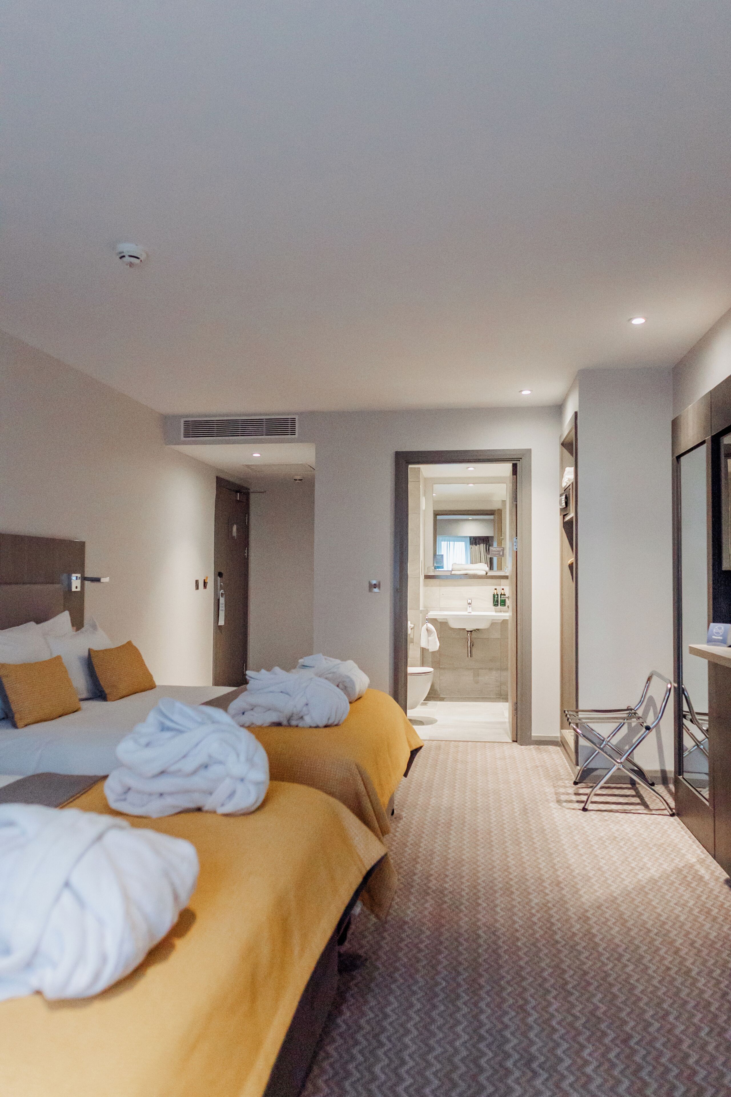 Quarto de hotel com uma cama, banheiro e escrivaninha.
