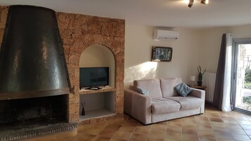 Una sala de estar con chimenea de piedra, televisor de pantalla plana, sofá y ventana con vistas.