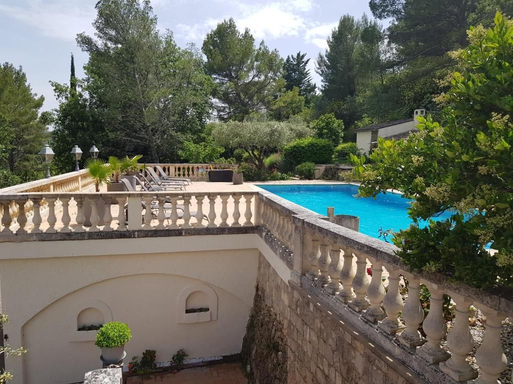A swimming pool with a stone balustrade, surrounded by lush greenery and trees.