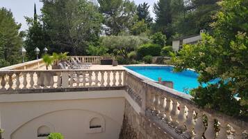 A swimming pool with a stone balustrade, surrounded by lush greenery and trees.