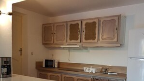 A kitchen with a central island, a microwave, a coffee maker, and cabinets above the counter. - Villa Manoé (Draguignan)