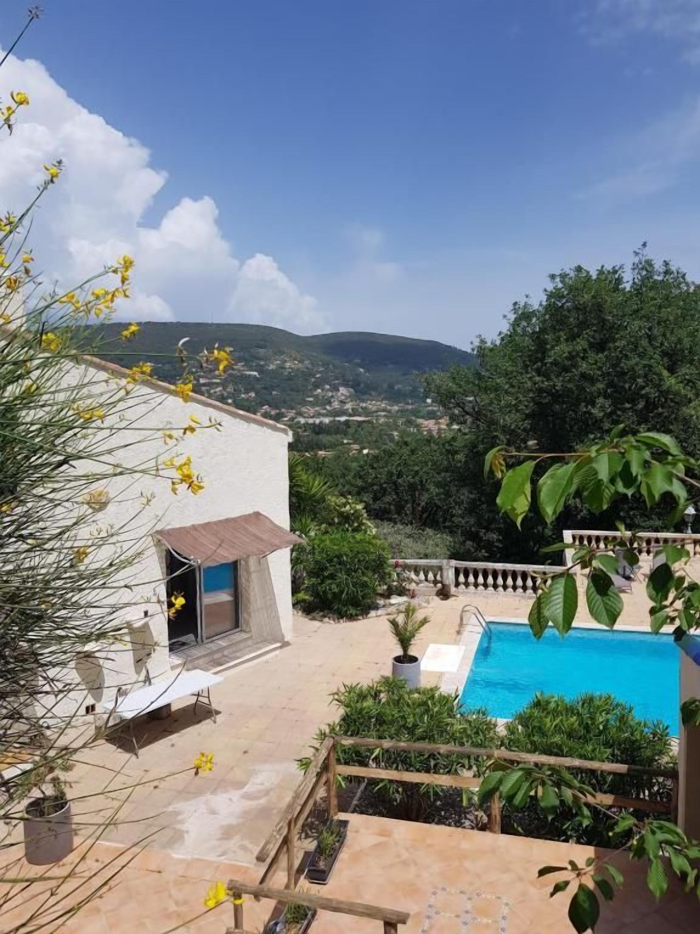 A residential property with a swimming pool, outdoor seating, and a view of the countryside.